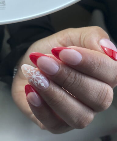 Ejemplo de tratamiento de manicura Nail Art. Uñas con la punta roja y una con dibujo de un copo de nieve